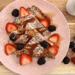 5 ingredient high protein French toast: image of French toast with powdered sugar, berries and sugar free maple syrup on wooden tray